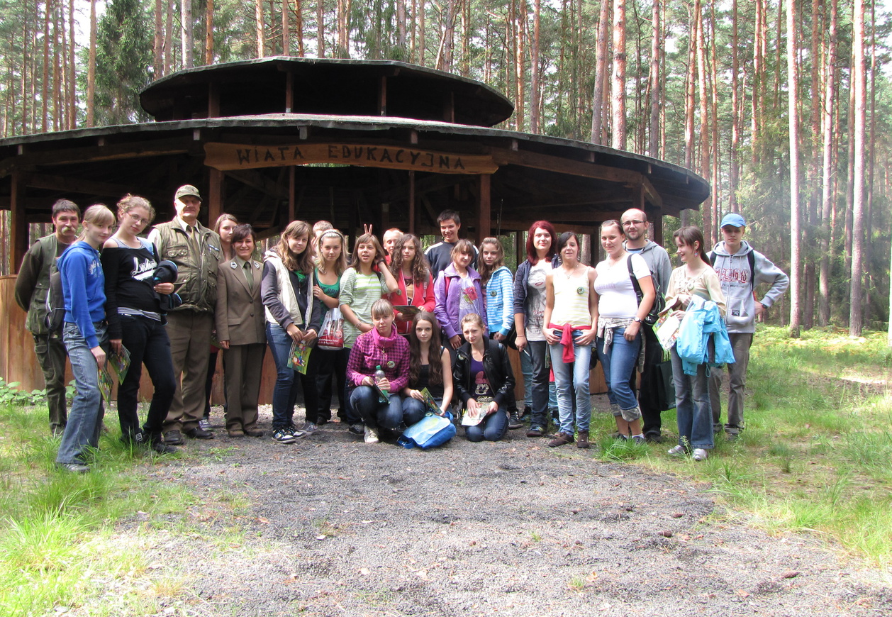 Brązowa drewniana wiata z grupą ludzi w kolorowych strojach