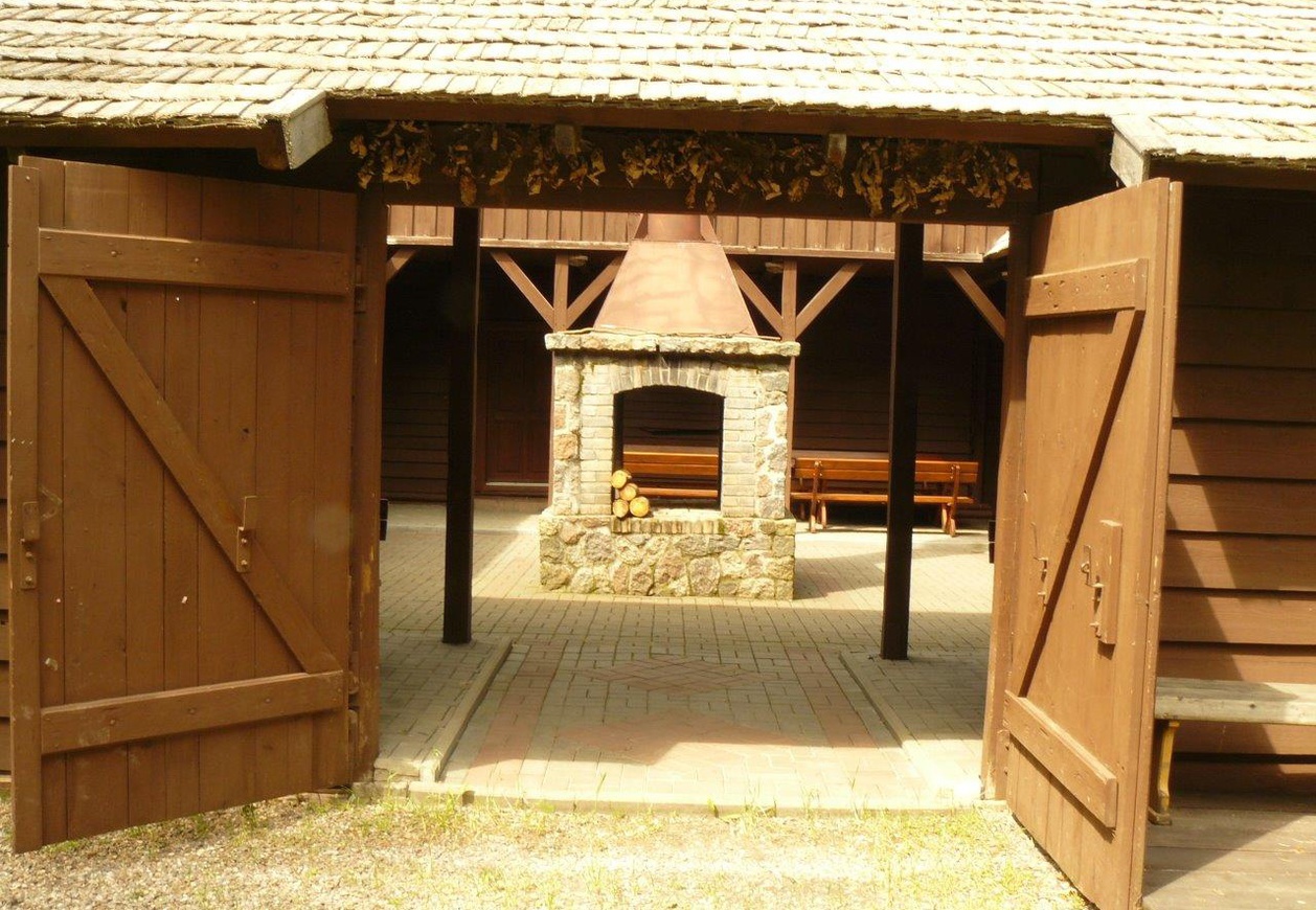 Zdjęcie kominka kamiennego za drewnianą, otwartą bramą.